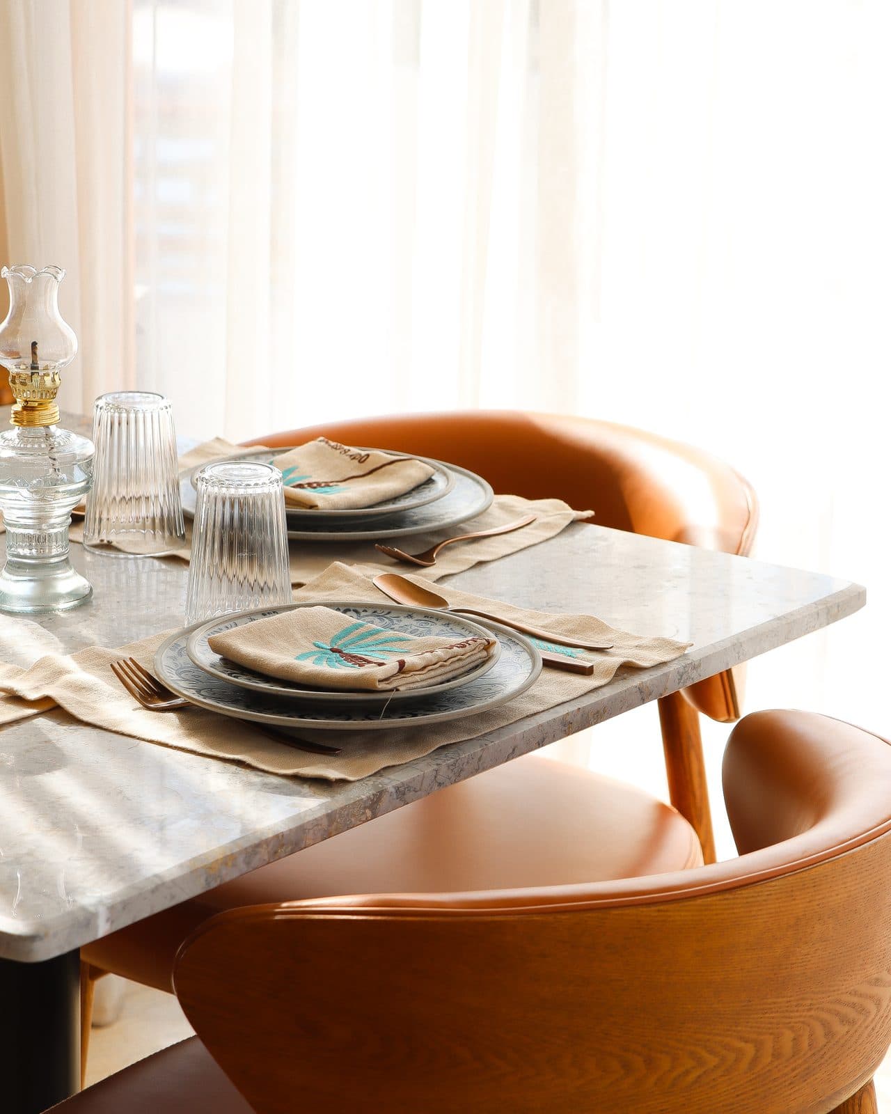 A marble table set beside leather chairs and a bright window